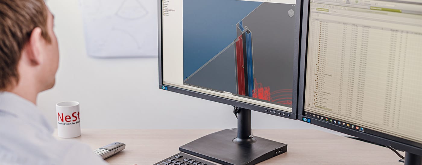 Vor Bildschirmen sitzender NeSt Konstrukteur arbeitet mit spezieller Software
